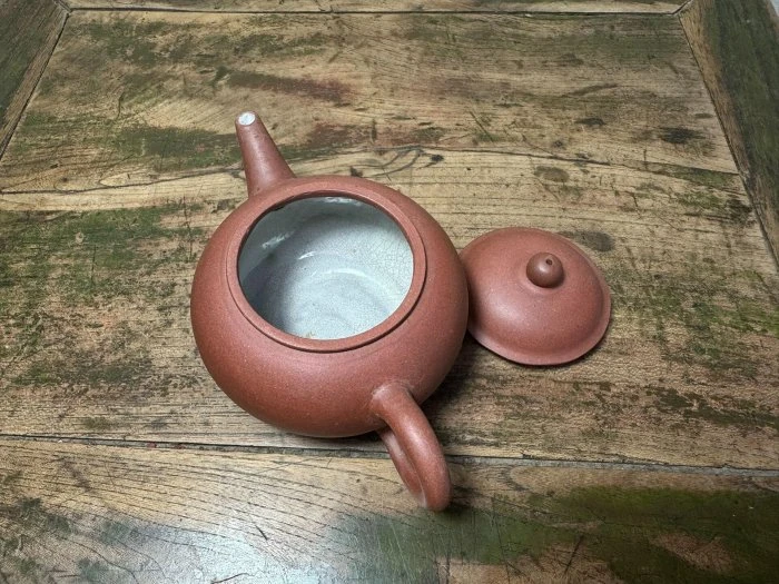 取下壺蓋的茶壺俯視照，壺口內呈淺色，壺蓋置於旁邊